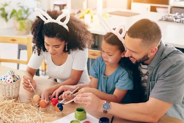A family painting Easter eggs at a table.