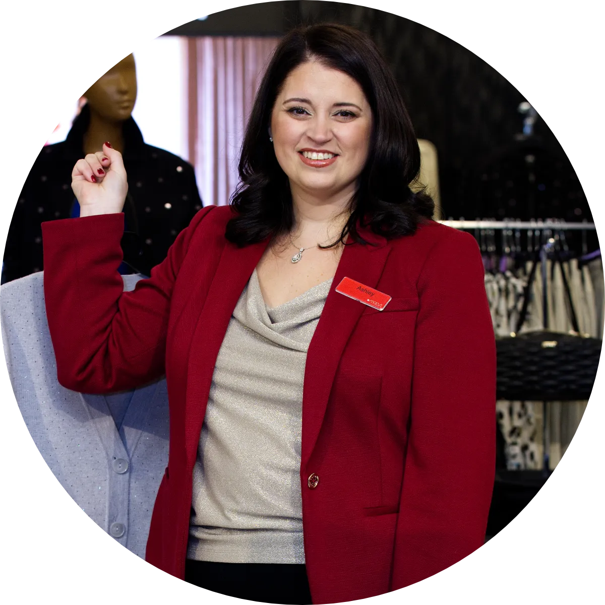 A representative from Macy's holds a shirt on a hanger behind herself while smiling for the camera.