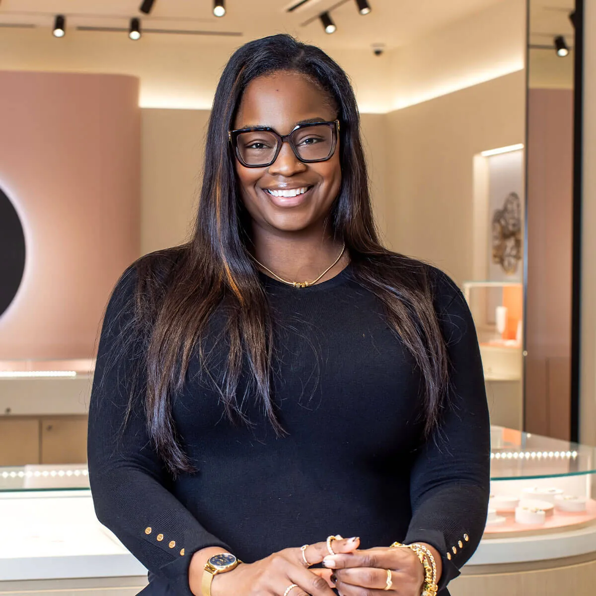 Ebony Davis smiles while standing in a modern, brightly-lit jewelry store with displays in the background.