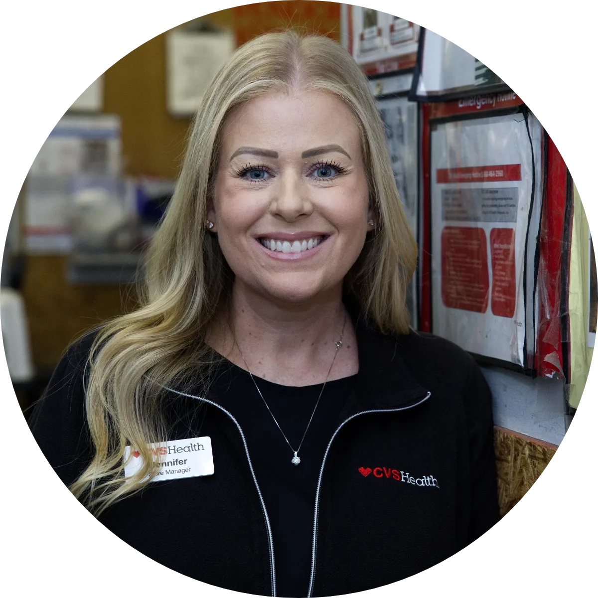 A representative from CVS Health, wearing a three-quarter zip, poses with a smile by a corkboard with employee signage.