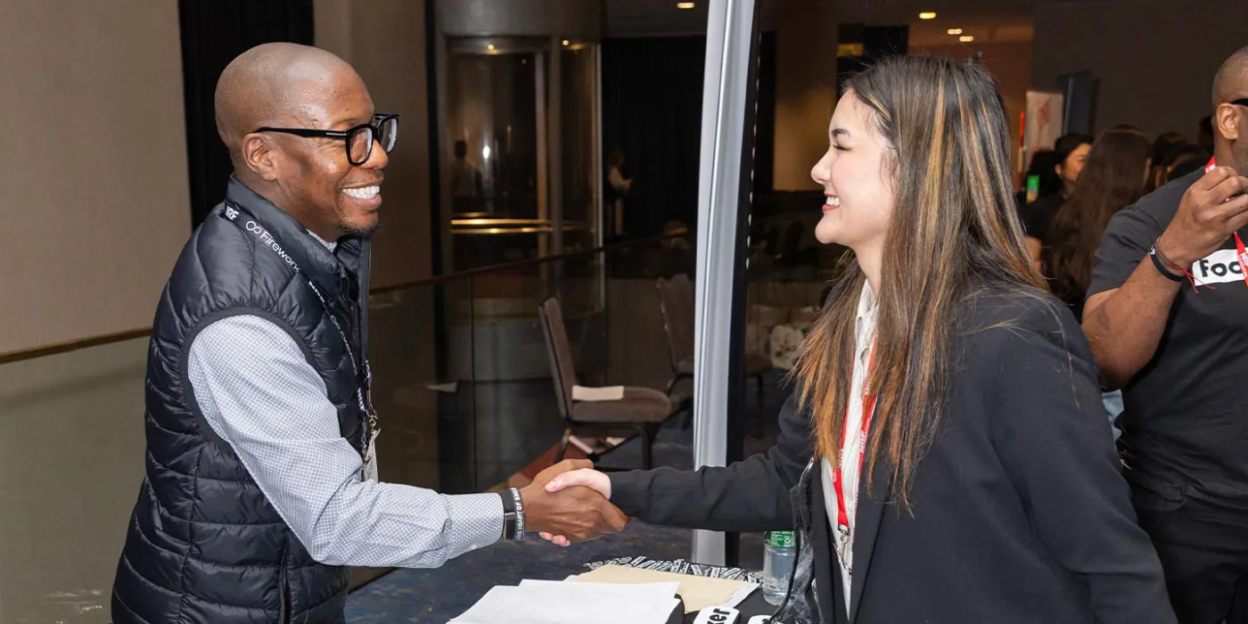A recruiter for a major retail company shakes the hand of a woman after a successful conversation at a career fair.