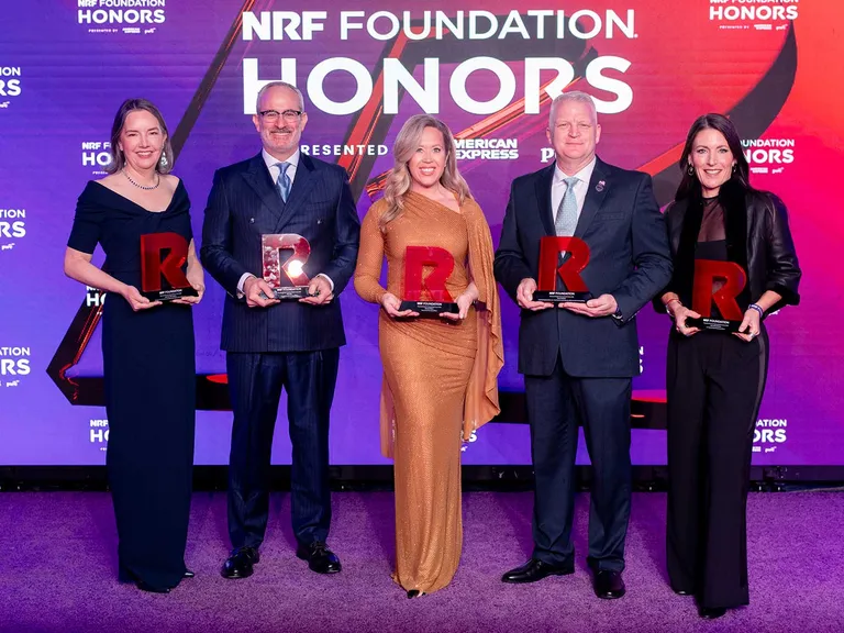The five winners of the The List honor from NRF pose in formal attire holding their awards at the NRF Foundation Honors event, standing against a purple and red backdrop.