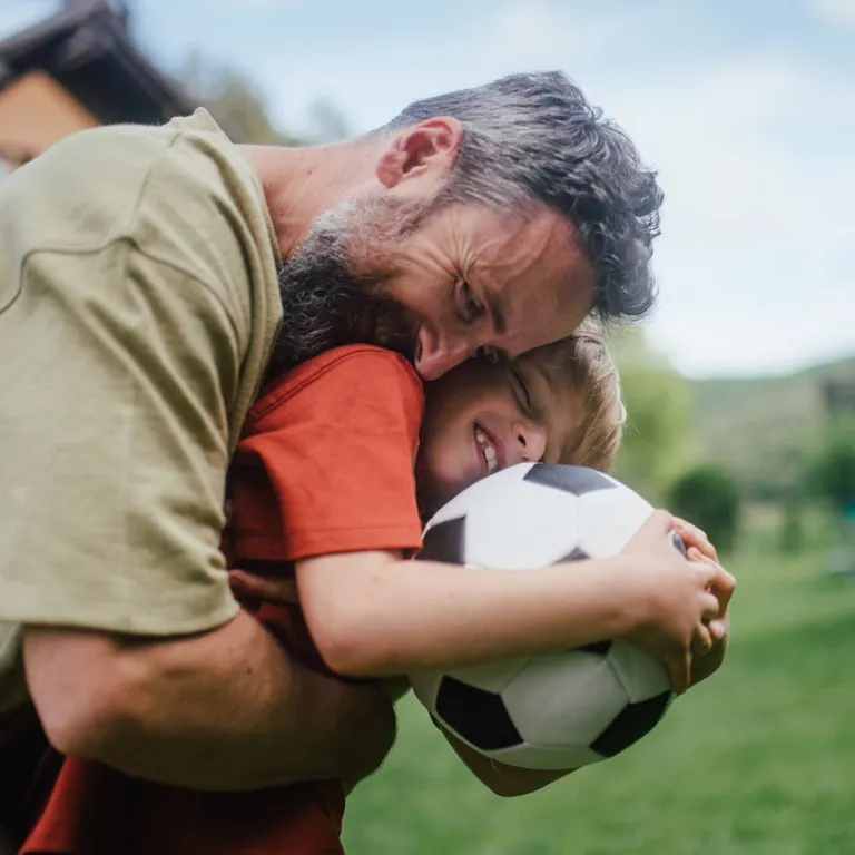 A father and son with a soccer ball.