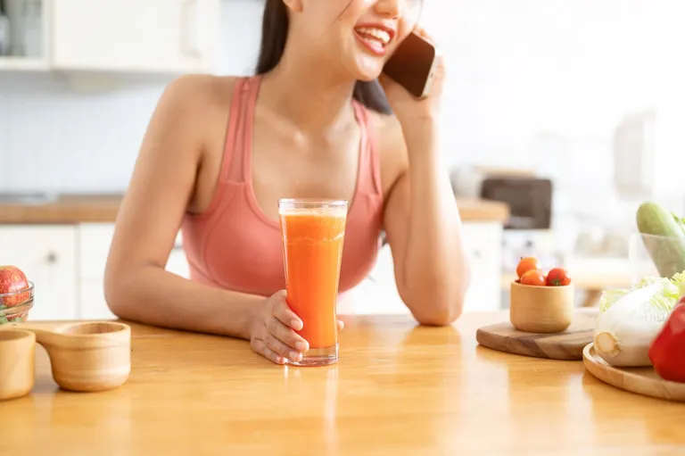 A woman talking on phone and drinking smoothie.