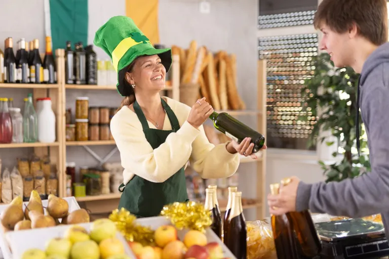 A retail worker dress in St. Patrick's Day accessories helping a customer.