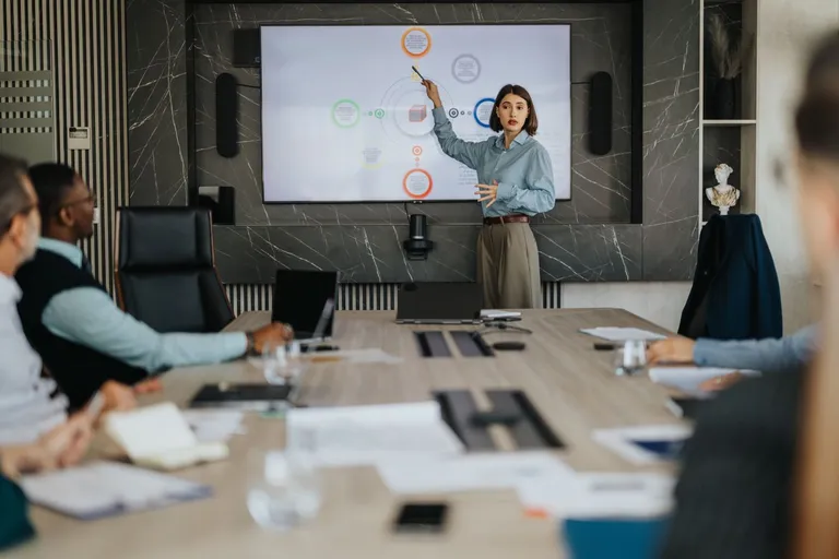 A woman points to a presentation in a business meeting