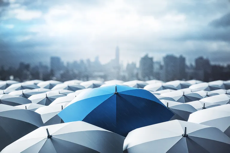 Blue umbrella under rainly skies with cityscape in the background