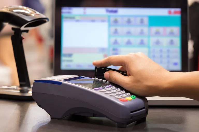 A customer swipes a credit card in a credit card reader at store