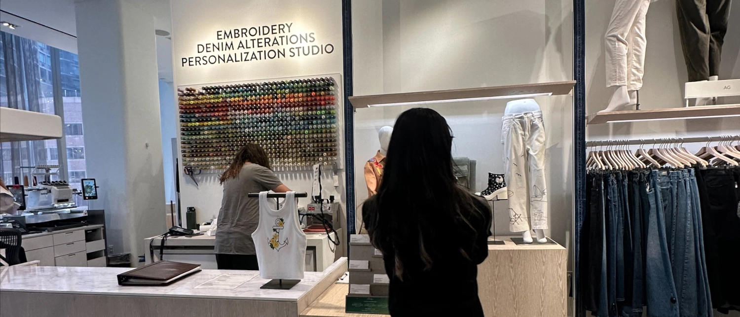 Two retail employees take of tasks surrounding the point of sale and jeans counter in a major retail store.