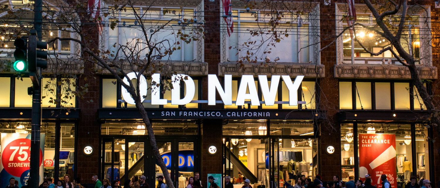 An Old Navy storefront in San Francisco. Dozens of shoppers are moving in and outside the store and giant sale and clearance banners hang in the windows.