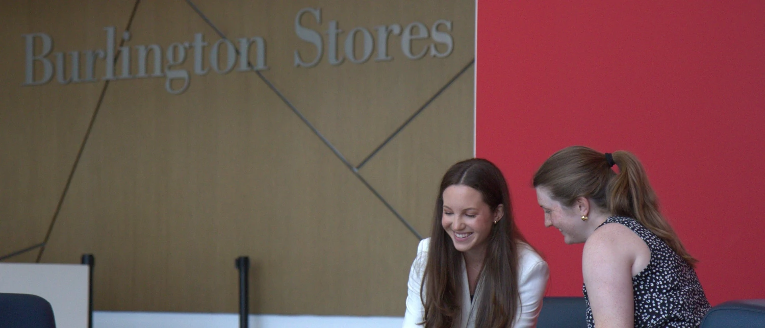Two Burlington employees review documents on a laptop (offscreen) in the Burlington Stores corporate office.