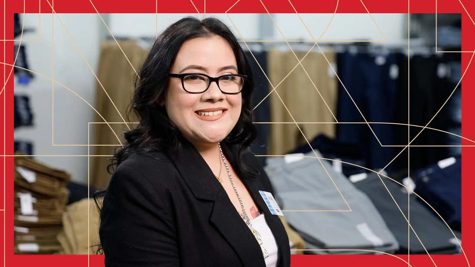 Senior Lead of Customer Service Rubi Huerta smiles in her store, in front of a table of pants. The photo has a red border and thin, gold, and geometric lines running through the background.