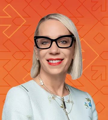 Professional portrait of Lorraine "Lo" Stomski, Chief Talent Officer for Walmart. The photo's background has a gradient of orange and red colors along with arrows pointing right, consistent with the NRF Foundation Student Program branding.