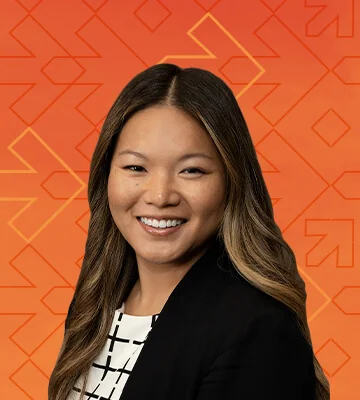 Professional portrait of Brenna McKeown. The photo's background has a gradient of orange and red colors along with arrows pointing right, consistent with the NRF Foundation Student Program branding.