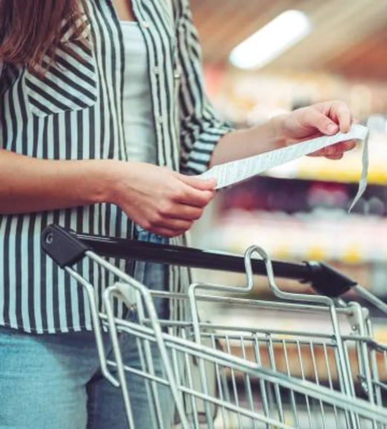 woman reading grocery list with a shopping cart