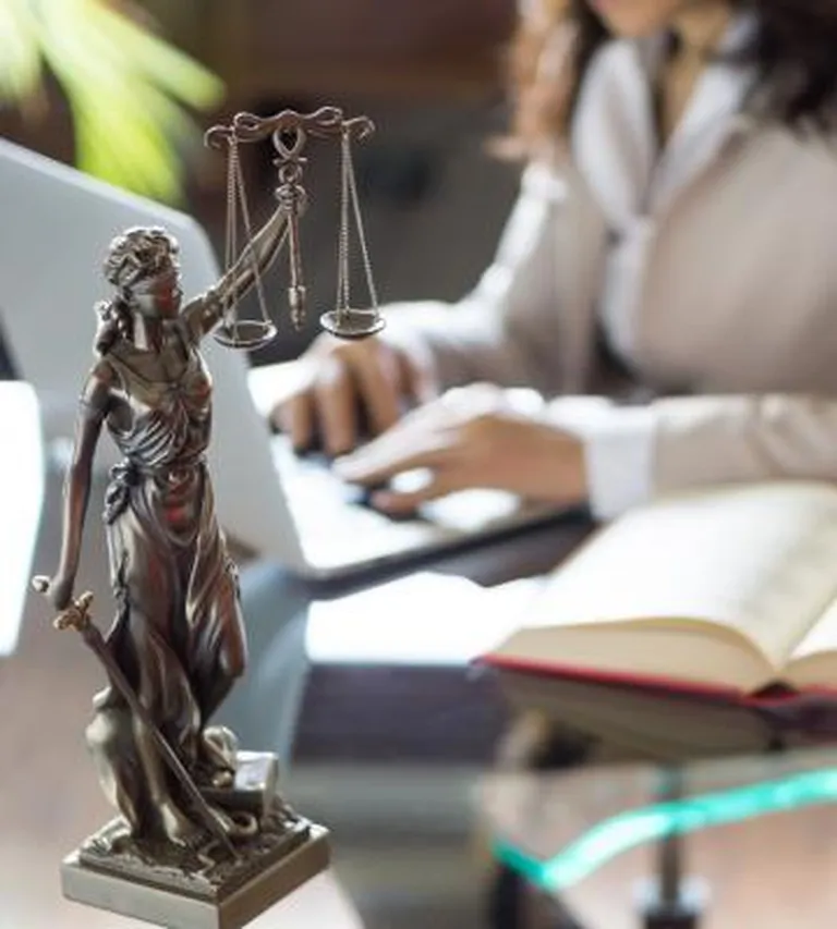 Law scales with a woman working on a computer in the background.