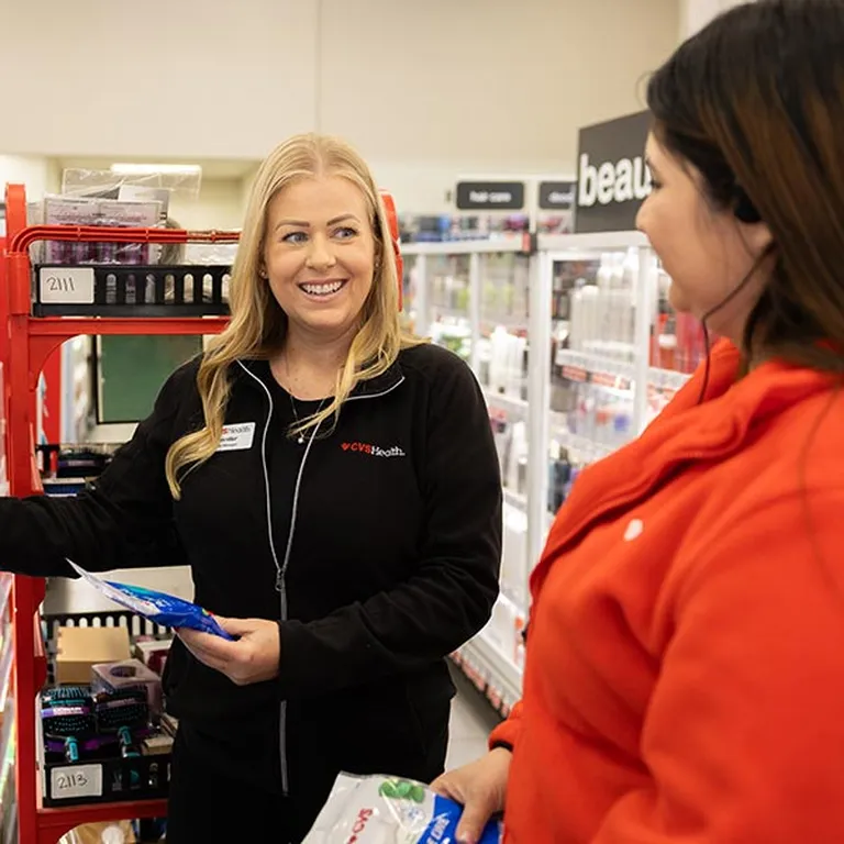 A CVS Health store leader works alongside another store associate to re-stock shelves within a CVS store.