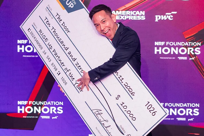 CEO of The Door, Kelsey Louie, poses with a large novelty check ($1,000) representing the RISE Up Partner of the Year award.