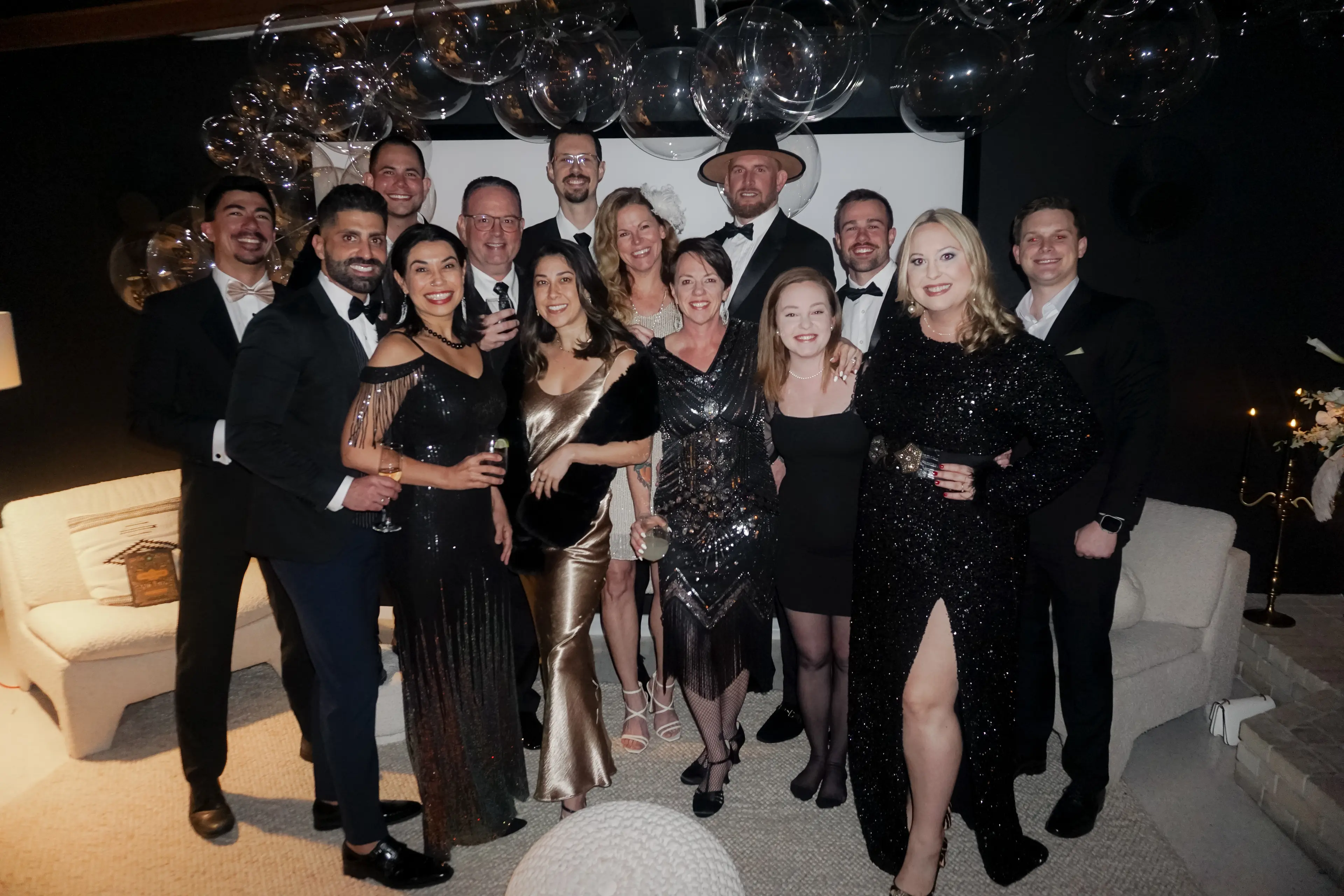 A group photo of the Friends of the Mills members smiling together at a party in Gainesville, Florida. The team is gathered in a festive indoor setting, celebrating their community partnership.