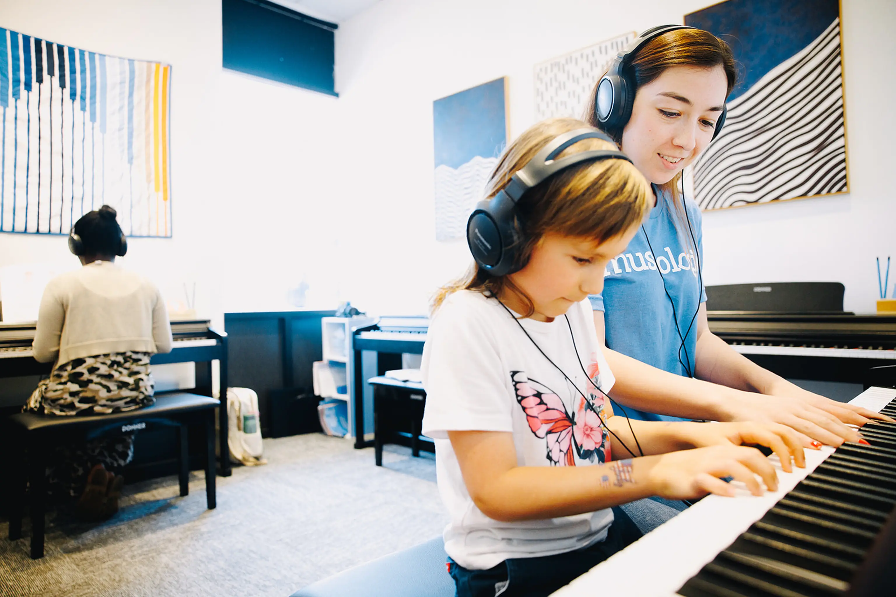 A young girl concentrates at the piano with her Musicologie Accelerated Lab teacher.