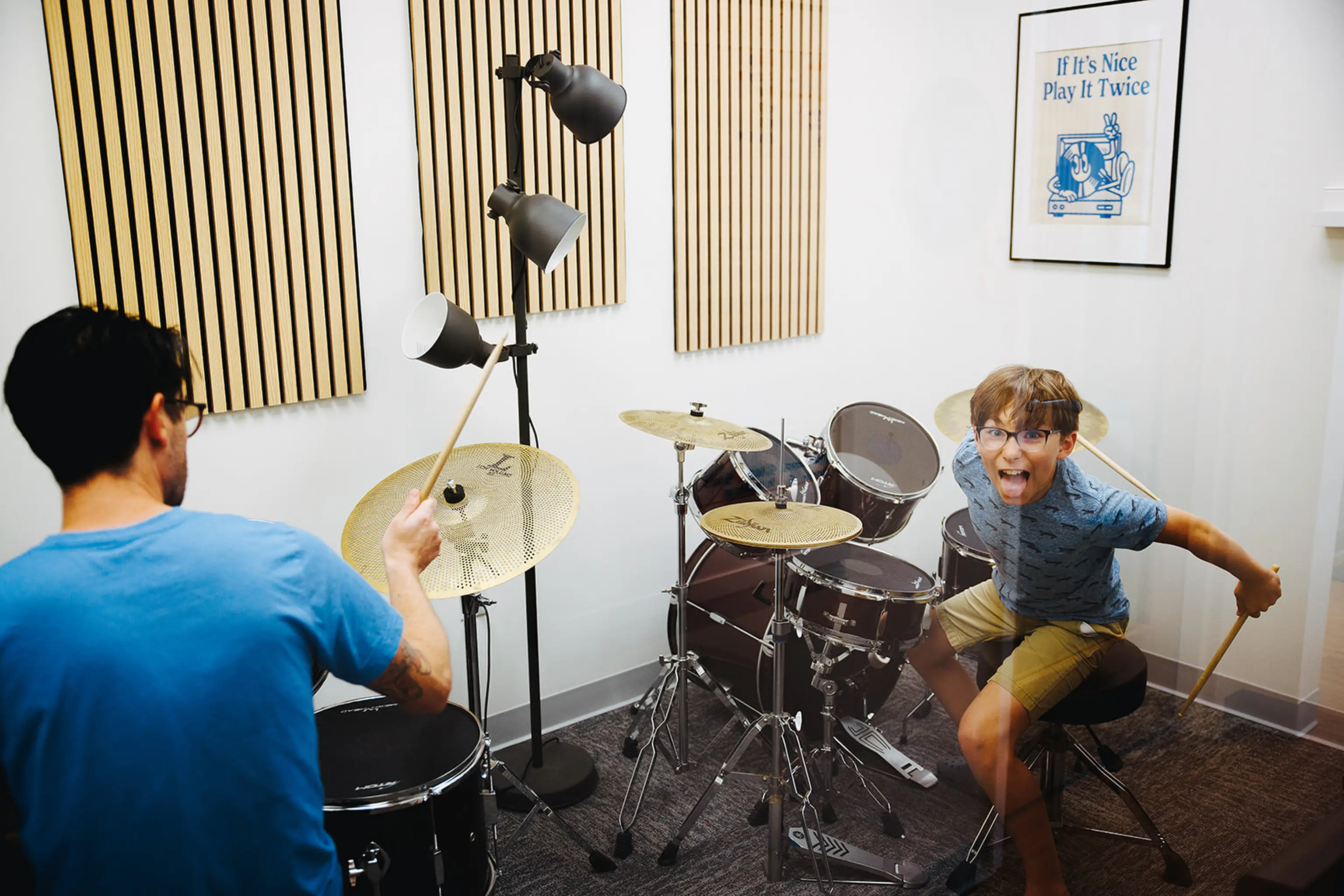 Young student being goofy at a drum kit during a lesson with a Musicologie teacher