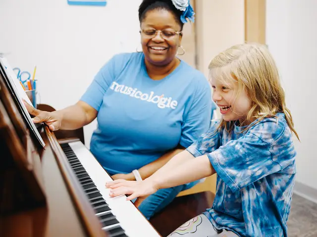 A young student laughs at the piano with her teacher during a lesson at Musicologie
