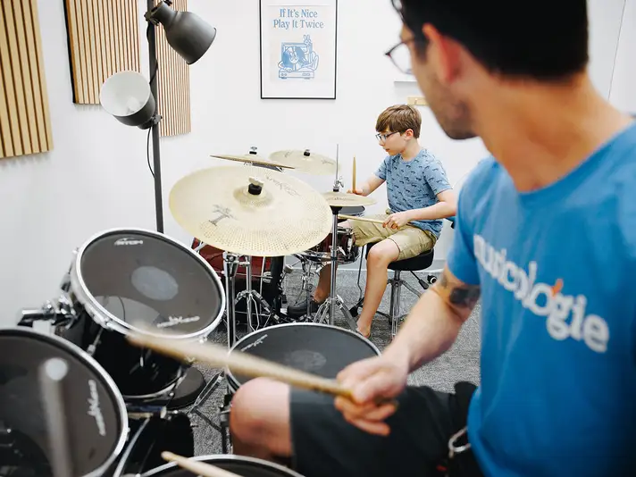 Musicologie teacher and young student playing separate drum kits during a drum lesson