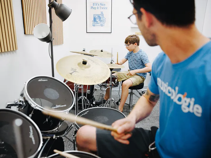 Musicologie teacher and young student playing separate drum kits during a drum lesson