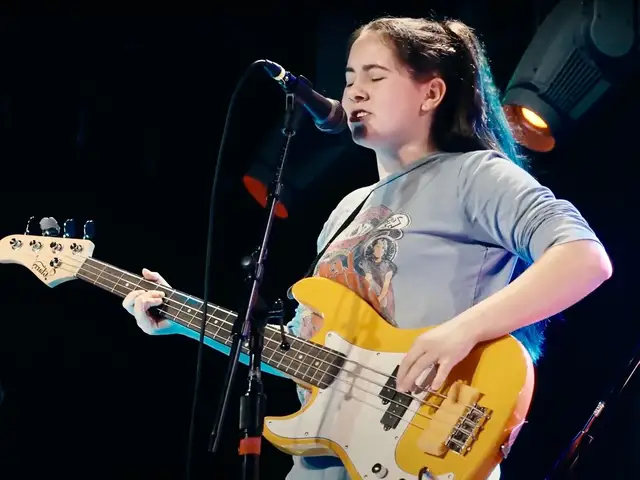 Girl playing bass and singing on stage