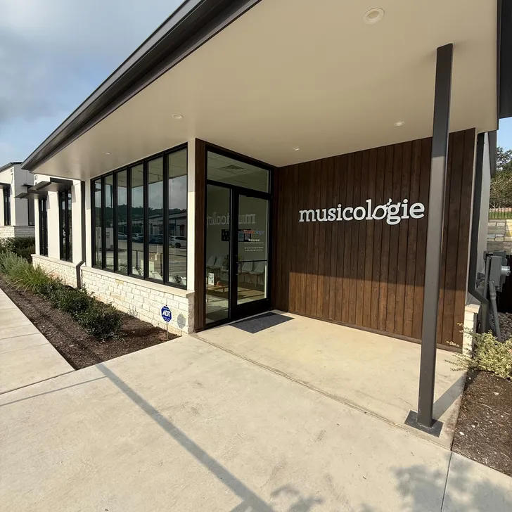 Girl playing piano in a piano lesson with her teacher sitting beside her