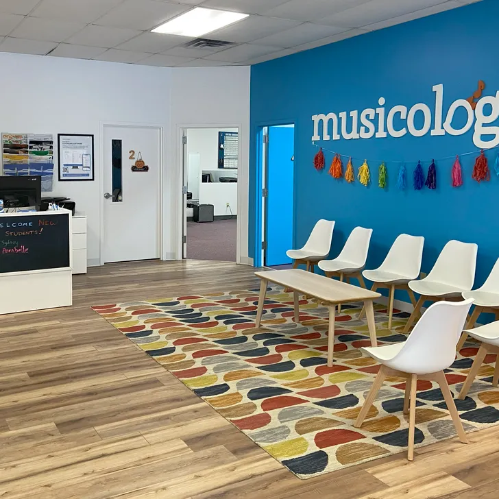 Girl playing piano in a piano lesson with her teacher sitting beside her