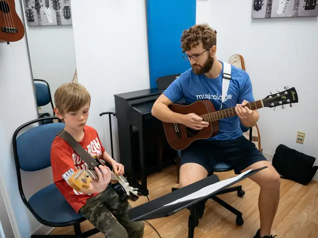 Boy playing the guitar with concentration in a lesson with a teacher