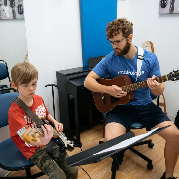 Boy playing the guitar with concentration in a lesson with a teacher