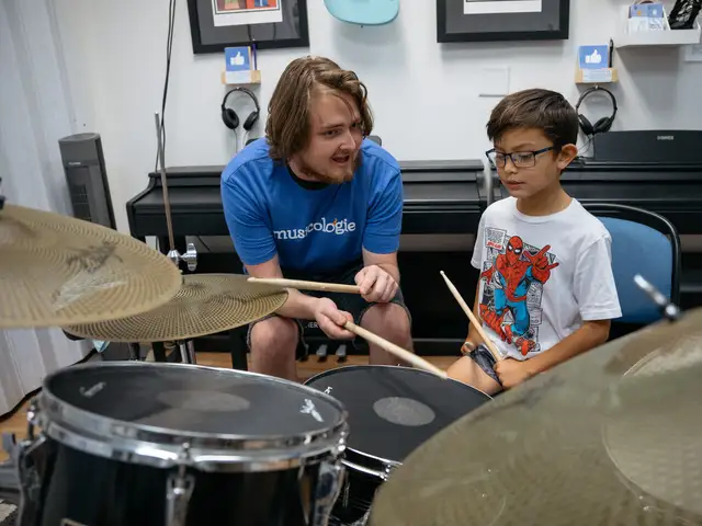 Boy sitting at the drums in a lesson with his teacher
