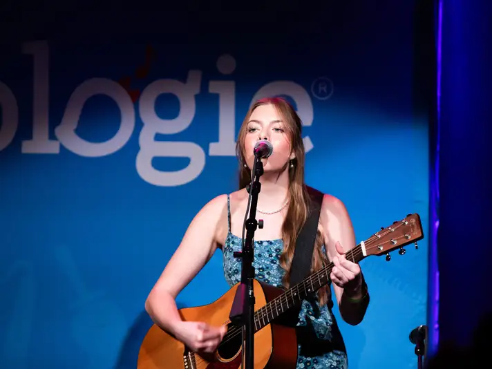 Woman on Stage with a Guitar Singing into a Microphone