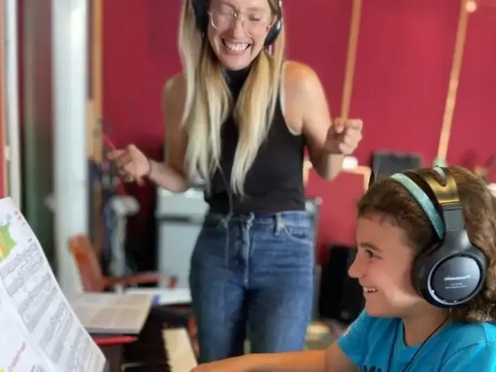 Accelerated Piano Lab student playing piano while their teacher smiles