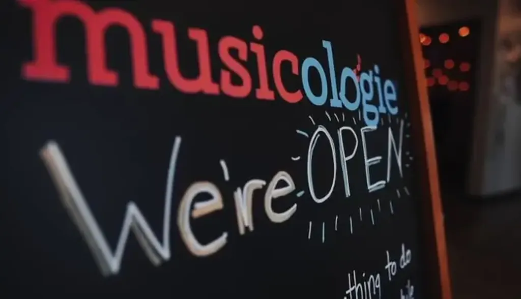 A welcoming Musicologie sandwich board that says "We're open!"
