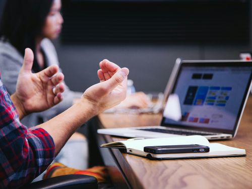 Hands gesturing in front of laptop in meeting