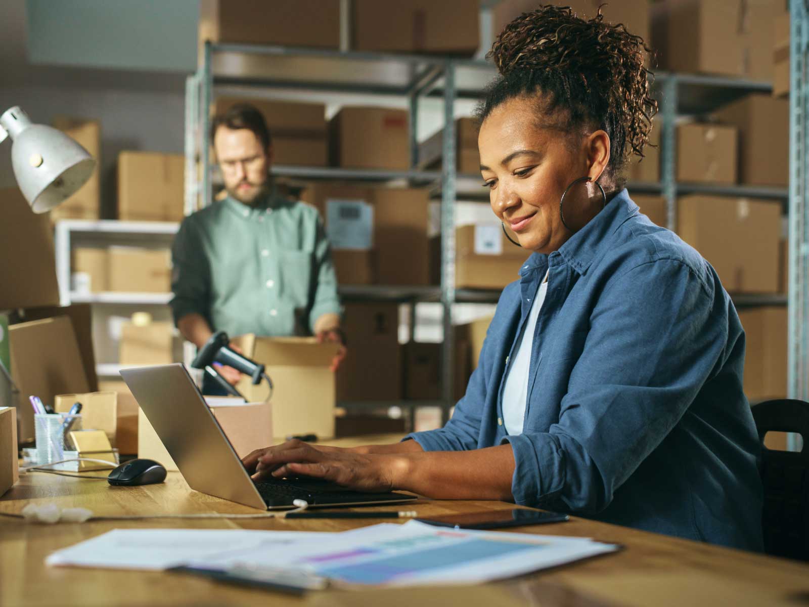 Woman in warehouse working on laptop