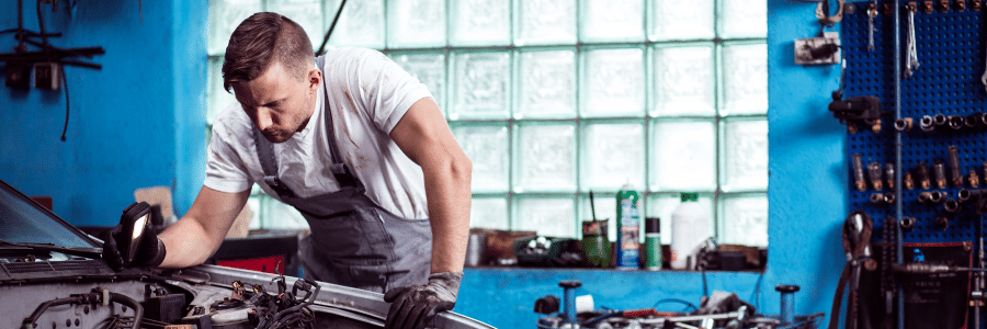 young man fixing up cars in a garage exploring the possibility of starting his own business. young man fixing up cars in a garage exploring the possibility of starting his own business.