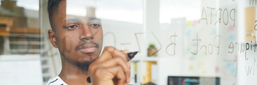 Male entrepreneur exploring calculations on a white board Male entrepreneur exploring calculations on a white board