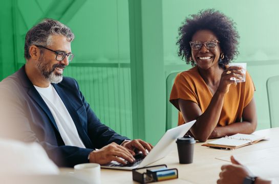 Business owners smiling during a meeting around a laptop