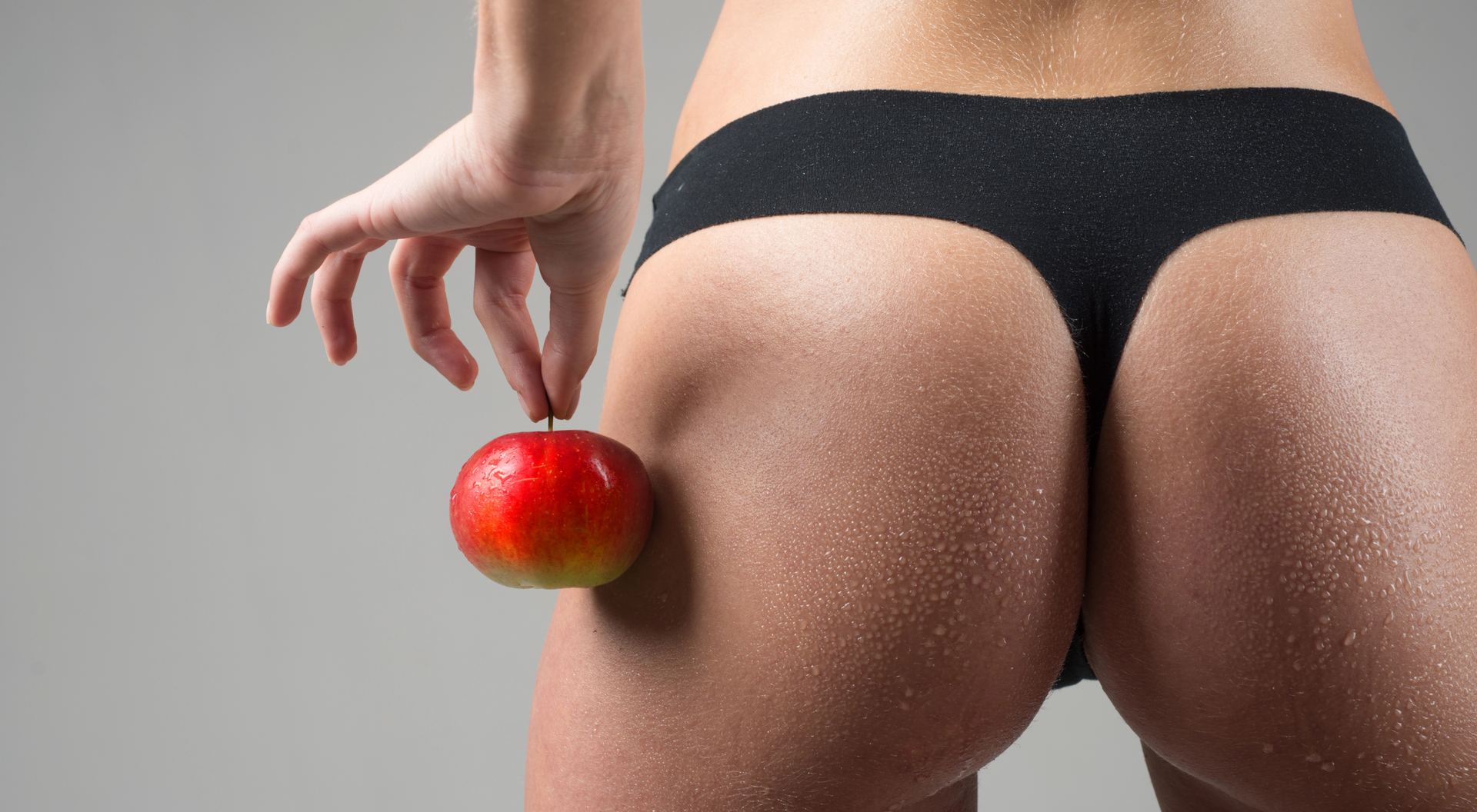 woman holding apple next to buttocks