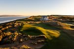Modern Scottish links on the Moray Firth with 16th-century castle ruins, the Scottish Highlands in the background, heather and gorse in bloom.