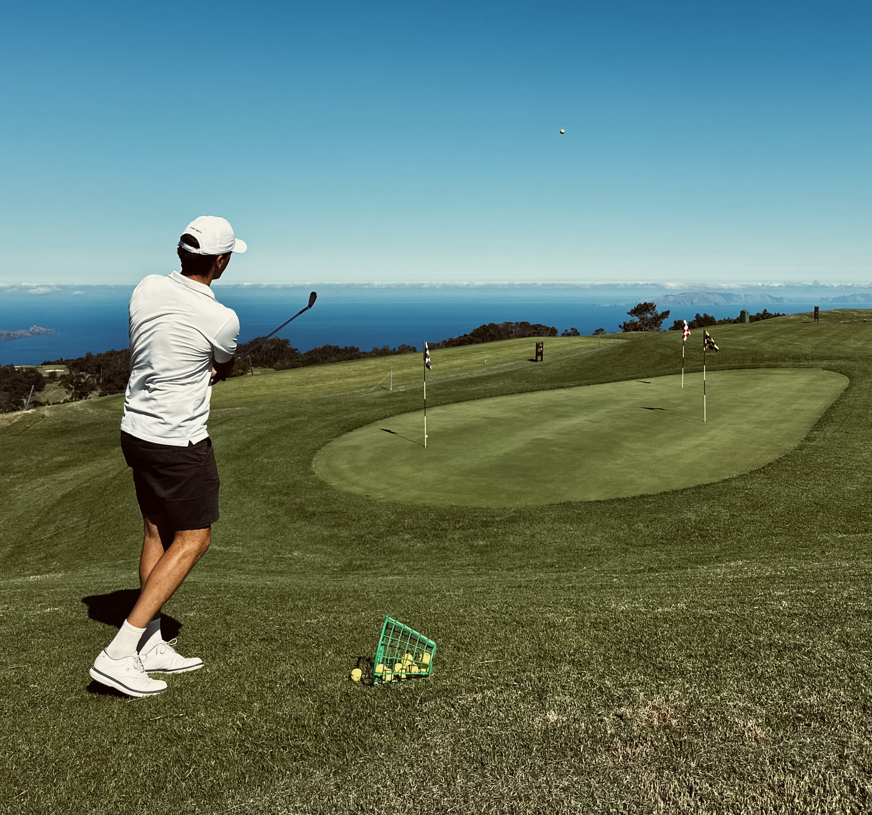 Golfer chipping to a clifftop practice green overlooking the sea