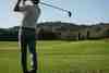 Golfer in mid-swing demonstrating controlled swing length for consistent iron distance