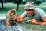 A humorous scene from Caddyshack showing a groundskeeper facing a mischievous gopher on the golf course - one of the most iconic moments in golf movie history.