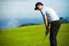Golfer chipping to a clifftop practice green above the sea