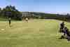 Golfers walking a fairway with trolleys on a sunny day