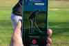 Golfer checking distances on the Hole19 GPS on a smartphone beside the fairway